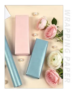 Detail von blauem und rosa perlmuttfarbenem Geschenkpapier mit Blumenakzenten.