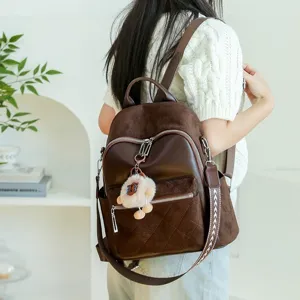 Stylish brown diamond quilted women's backpack with cute fur ball charm