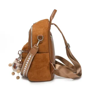 Brown suede and faux leather women's backpack featuring a decorative wide strap and charm