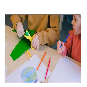 Kinder verwenden grünes Geschenkpapier für kreative DIY-Bastelprojekte an einem Tisch.