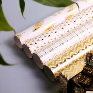 Luxuriöse Geschenkpapierrollen mit Goldfolie und eleganten geometrischen Mustern.