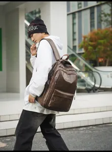 Hombre con una mochila grande de cuero marrón vintage en un entorno urbano.