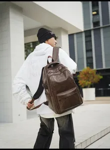 Modelo masculino con una gran mochila de cuero marrón vintage en un entorno urbano