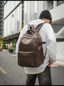 Hombre con una gran mochila de cuero vintage marrón en un entorno urbano elegante