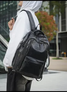Detalle de una mochila de cuero sintético negro retro llevada por un modelo