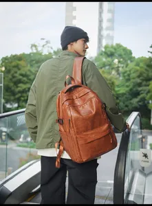 Mochila grande de cuero sintético marrón de estilo vintage llevada por un modelo hombre.