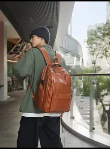 Modelo asiático con una gran mochila vintage de cuero sintético marrón en entorno urbano