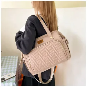 Große beige multifunktionale Wickeltasche, an der Schulter getragen in Lifestyle-Szene