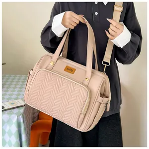 Detailansicht einer rosa Wickeltasche mit Steppmuster und Logo-Patch im modernen Design