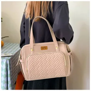 Detailaufnahme einer beigefarbenen Wickeltasche, die von einer Frau getragen wird.