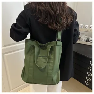 Detail of the large green canvas tote bag worn as a shoulder bag on a model