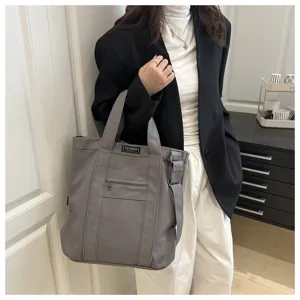 Large grey canvas tote bag shown being carried by a model in casual professional attire