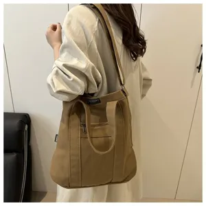 Large khaki canvas shoulder bag for women styled in a casual minimalist indoor setting