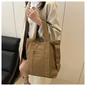Asian model showcasing a brown vintage canvas tote bag with an adjustable shoulder strap