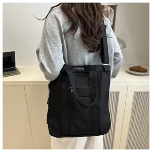 Stylish large black canvas tote bag with adjustable shoulder strap and fashion label
