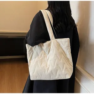 Vista trasera de modelo con un elegante bolso tote acolchado blanco sobre un abrigo negro