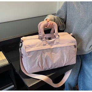 Close-up of a large pink multi-functional travel duffel bag with a sturdy shoulder strap