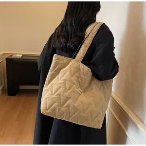 Vista detallada del patrón en 'V' acolchado en un bolso tote grande beige de mujer