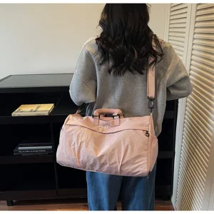 Back view of a woman carrying a pink lightweight multi-functional travel bag with strap
