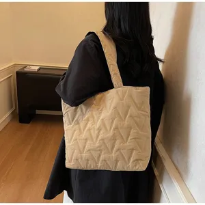 Detalle de un bolso tote acolchado beige de gran capacidad con costuras en V al hombro.