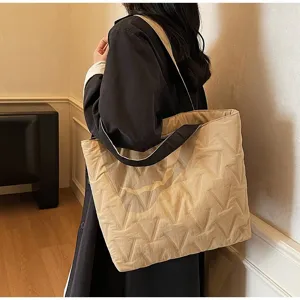 Vista detallada de un bolso tote de lona acolchada beige con patrón en V