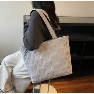 Detalle de un bolso tote acolchado gris grande con un elegante patrón en V para mujer