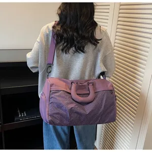 Detailed back view of a woman carrying a large purple checkered travel and gym bag