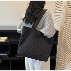 Vista detallada de un bolso tote negro acolchado llevado por una modelo en un ambiente moderno