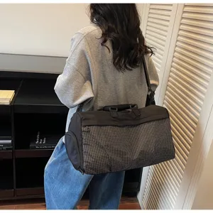 Close-up detail of a large black travel gym bag with grey grid pattern carried by a model
