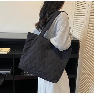 Vista lateral de un gran bolso tote acolchado negro llevado por una modelo elegante