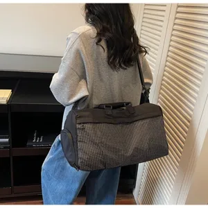 A side view of a large capacity checkered travel and gym bag being carried on the shoulder
