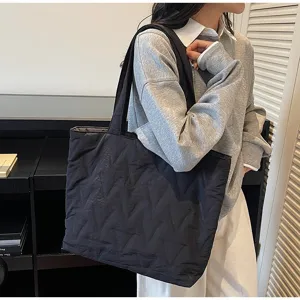 Bolso tote negro acolchado de gran capacidad llevado por una modelo en interior