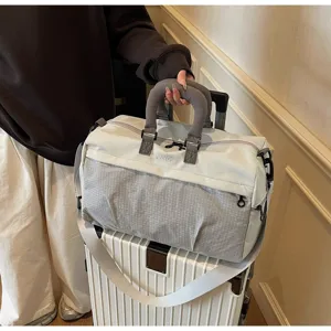 Detail of grey travel bag with luggage strap sleeve on a white rolling suitcase