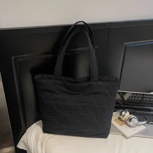 Bolso tote negro acolchado de lona para mujer, ideal para el trabajo o uso diario.