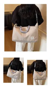 Grand sac de voyage beige porté par un mannequin de dos dans un cadre intérieur