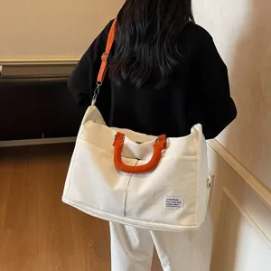 Vue détaillée d'un grand sac de voyage blanc avec poignées oranges et bandoulière réglable