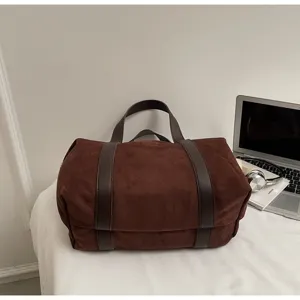 Vista dettagliata di una borsa da viaggio vintage in pelle scamosciata marrone su tavolo.
