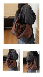 Primo piano di una borsa da viaggio retrò marrone capiente indossata a spalla con stile.