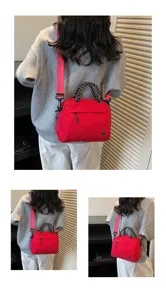 Fashionable red nylon crossbody handbag with woven handles worn by a model in a casual setting