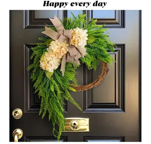 Artificial hydrangea wreath with burlap bow hanging on a black farmhouse door