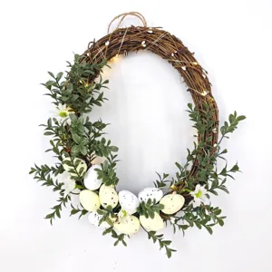 Close-up detail of Easter wreath with speckled eggs, green foliage, and warm LED lights.
