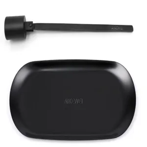 Detail of matte black stainless steel candle snuffer and oval metal accessory tray