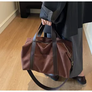 Dettaglio borsa da viaggio in pelle scamosciata marrone con manici in pelle e zip oro