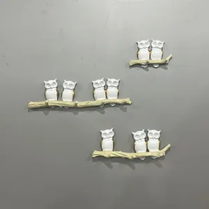 Detailed view of three decorative owl wall hooks on creative branches against a grey wall