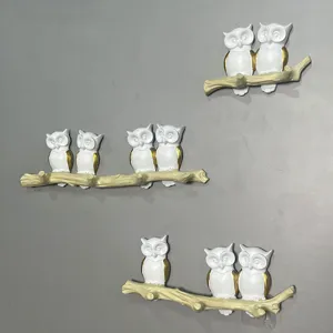 Detailed view of hand-painted owl branch wall hooks with white and gold accents