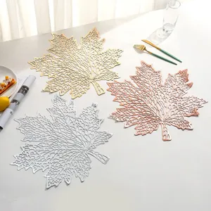 Detailed view of three hollowed-out maple leaf PVC placemats in metallic colors