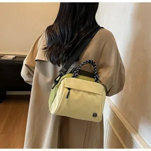 Lightweight minimalist yellow and green crossbody bag shown on a person wearing a beige coat