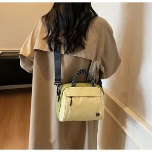 Detail view of a light yellow nylon crossbody bag worn over a beige trench coat.