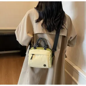 Rear view of model wearing a stylish cream and green crossbody bag with rope handles