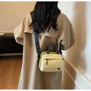 Rear view of a stylish two-tone yellow crossbody bag worn with a beige trench coat